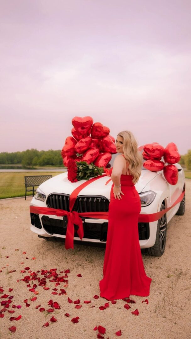A woman in red dress standing next to a car.
