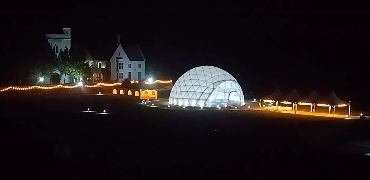 A large white dome is lit up at night.