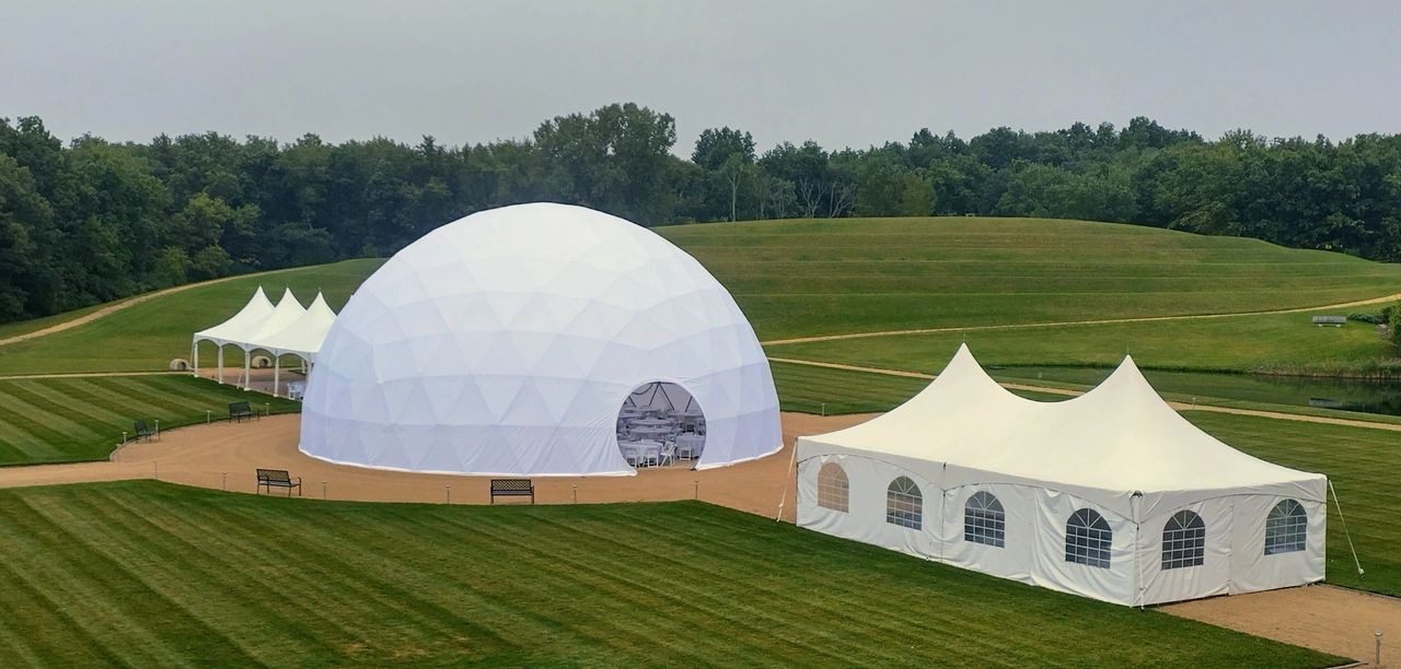 A large white tent in the middle of a field.
