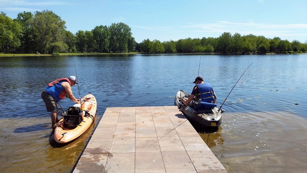 Two people are fishing from a boat on the water.