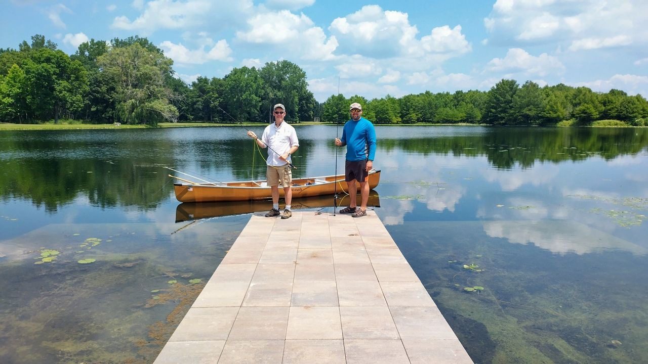 Two men standing on a dock with a canoe.