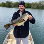 A man holding a large fish on top of a boat.
