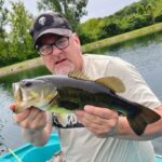 A man holding a fish while standing on top of a boat.