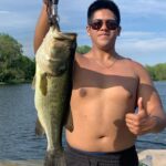 A man holding up a large fish on the shore.