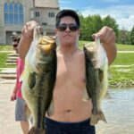 A man holding two large fish in his hands.