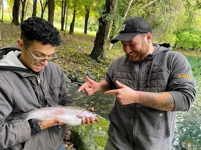 Two men holding a fish in their hands.
