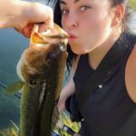 A woman is holding a fish and eating it.