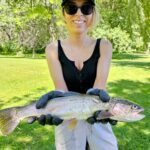 Person holding a large fish outdoors on a sunny day.