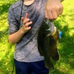 A person holding a freshly caught fish outdoors.