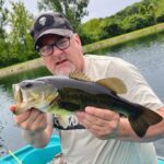 Man proudly holding a large fish he caught outdoors.