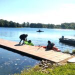People preparing for a water activity on a lakeside dock.