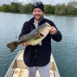 Man proudly holding a large fish on a boat.