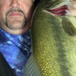 Man holding a large fish close to the camera.