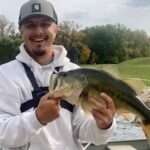 Man smiling and holding a large fish outdoors.