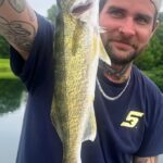 Man proudly holding a large fish he caught outdoors.