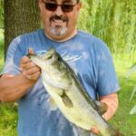 Man holding a large fish in a park.