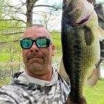 Man in sunglasses holding a large fish outdoors.