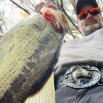 Man proudly holds a large fish he caught.