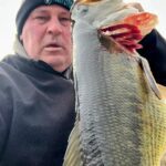 Man proudly holding a large fish he caught.