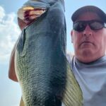 Man holding a large fish outdoors.
