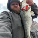 Man holding a large fish, showing a proud catch outdoors.
