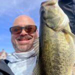 Man proudly holding a large fish he caught outdoors.