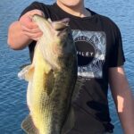 Person holding a large fish by the water.