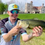 A man proudly holding a large fish outdoors on a sunny day.